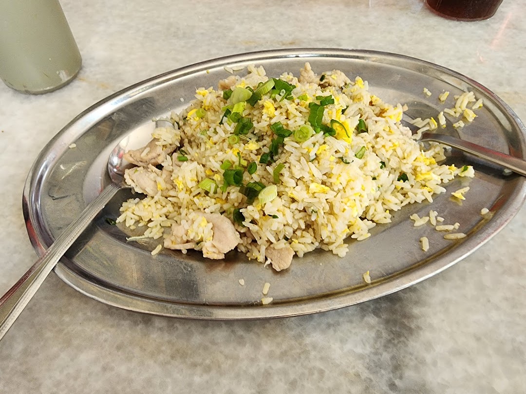 A close-up of a plate of fried rice with chicken, egg, and green onions on a metal platter.