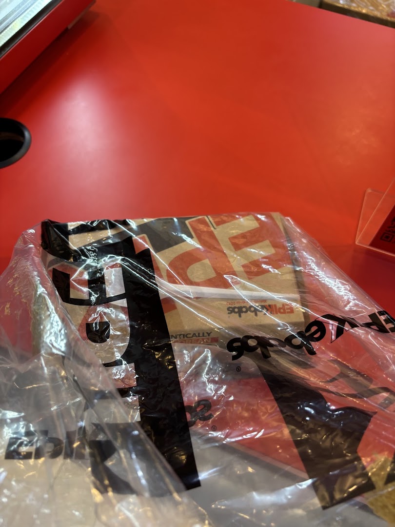 A plastic bag containing EPIKebabs food packaging rests on a vibrant red counter, ready for takeaway.