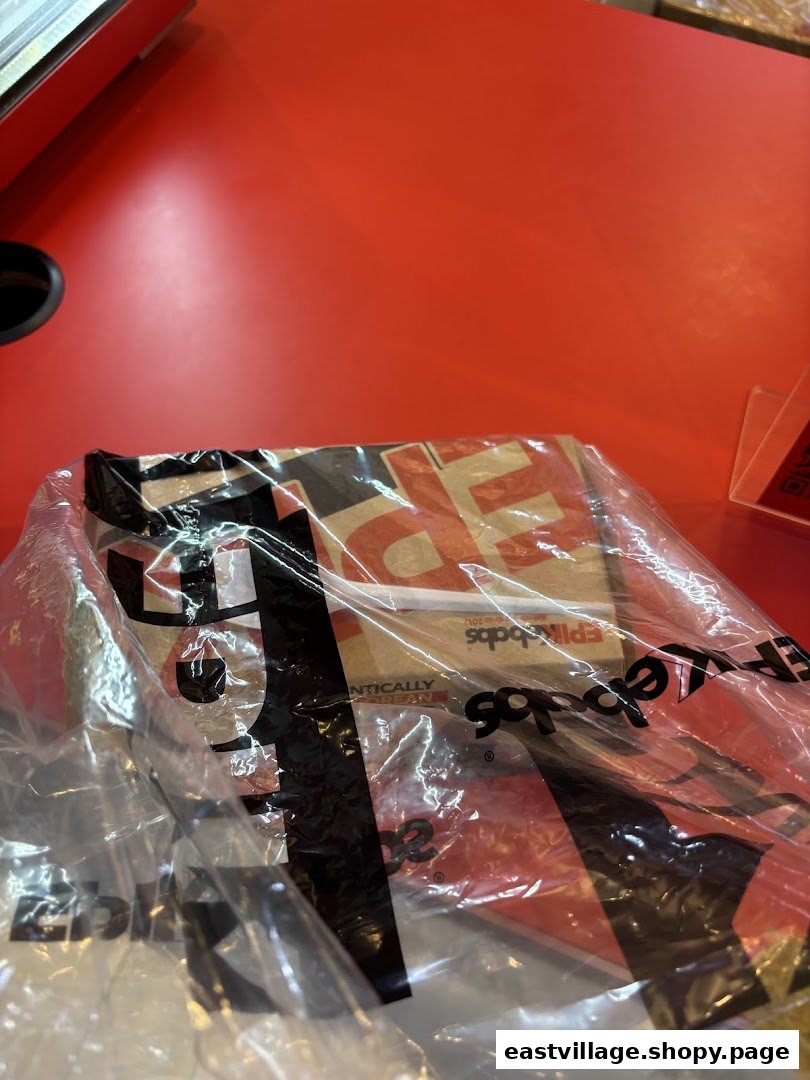 A plastic bag containing EPIKebabs food packaging rests on a vibrant red counter, ready for takeaway.