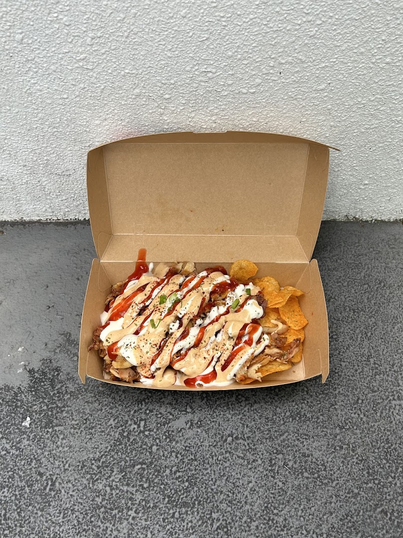 A delicious box of loaded chips topped with meat, sauces, and seasonings, ready to enjoy.