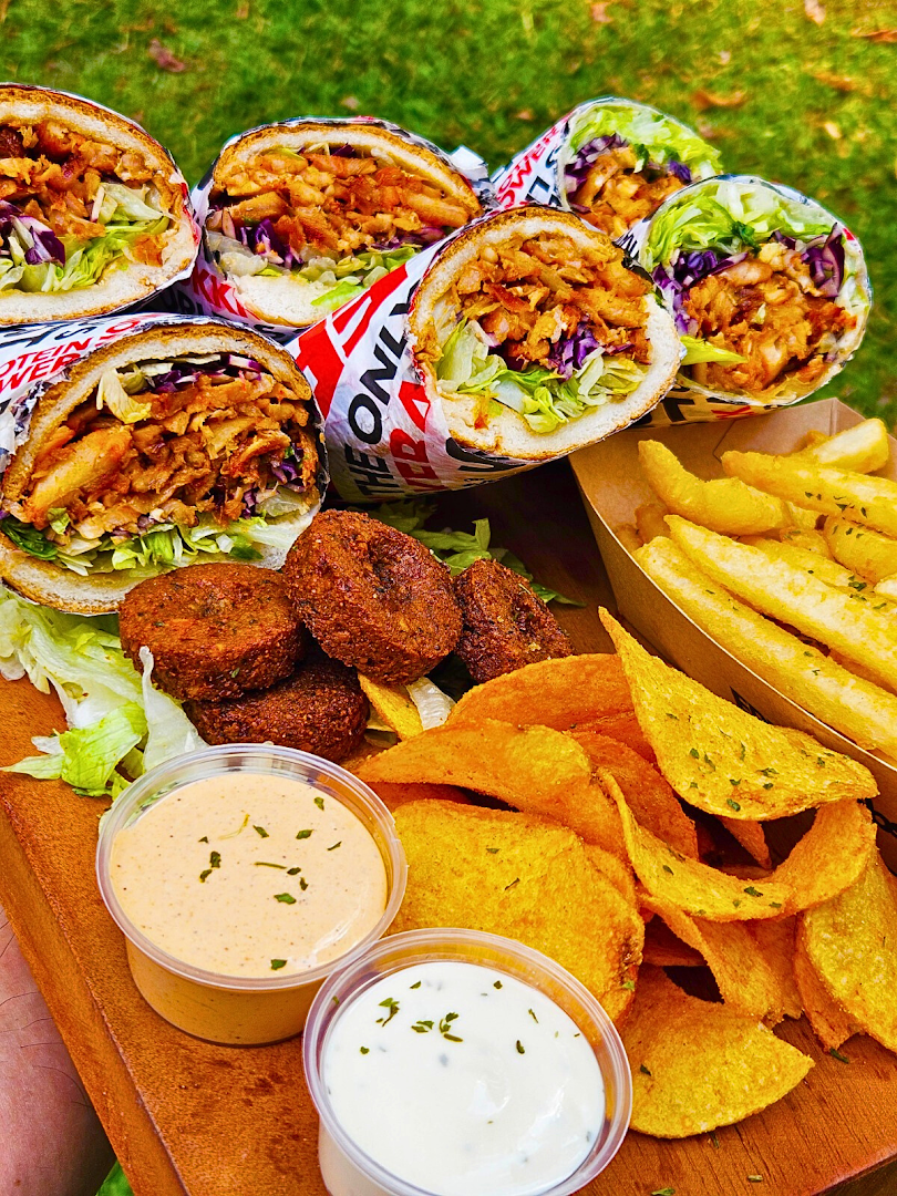 A vibrant platter featuring several kebabs, falafel, crispy chips, and two dipping sauces.
