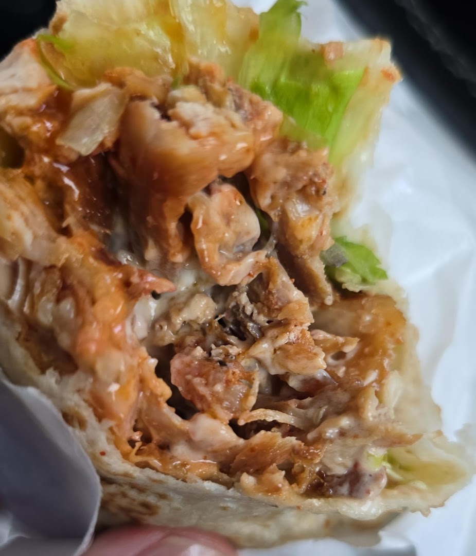 A close-up view of a delicious kebab or wrap filled with succulent meat, creamy sauce, and fresh lettuce.