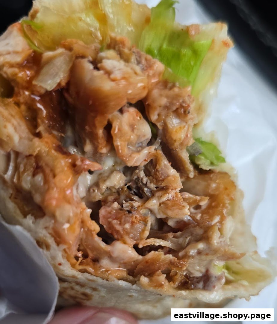A close-up view of a delicious kebab or wrap filled with succulent meat, creamy sauce, and fresh lettuce.