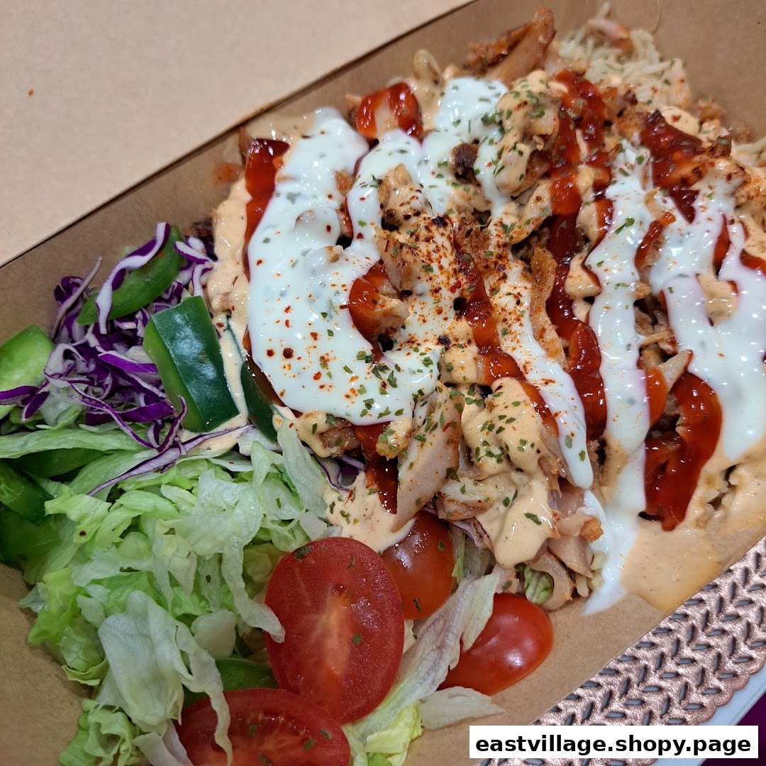 A close-up of a delicious kebab plate featuring meat, rice, fresh salad, and creamy sauces.