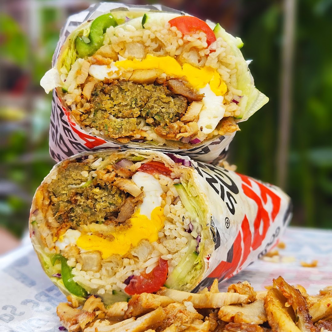 Two large, cut-open kebabs revealing falafel, rice, vegetables, and egg fillings.