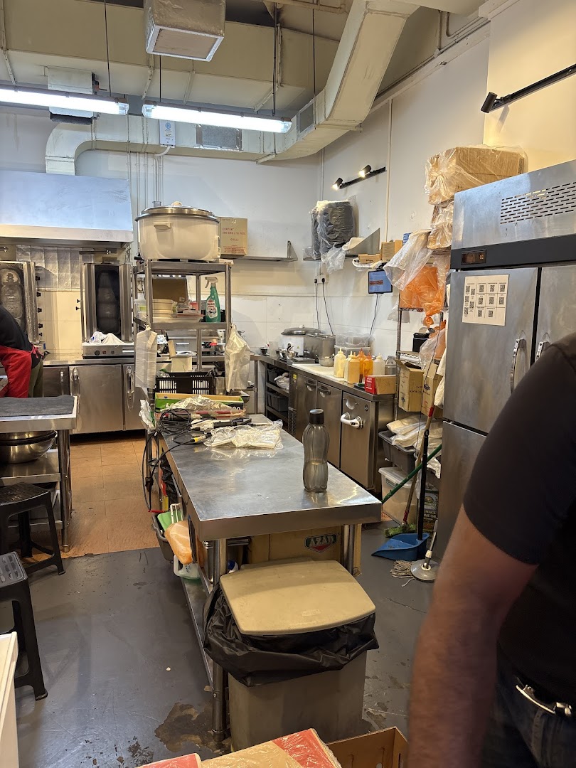 A bustling commercial kitchen with stainless steel counters, equipment, and a large rotisserie.