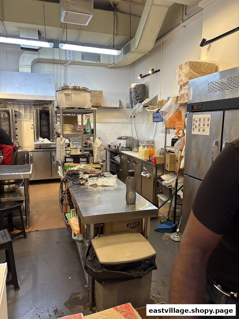 A bustling commercial kitchen with stainless steel counters, equipment, and a large rotisserie.