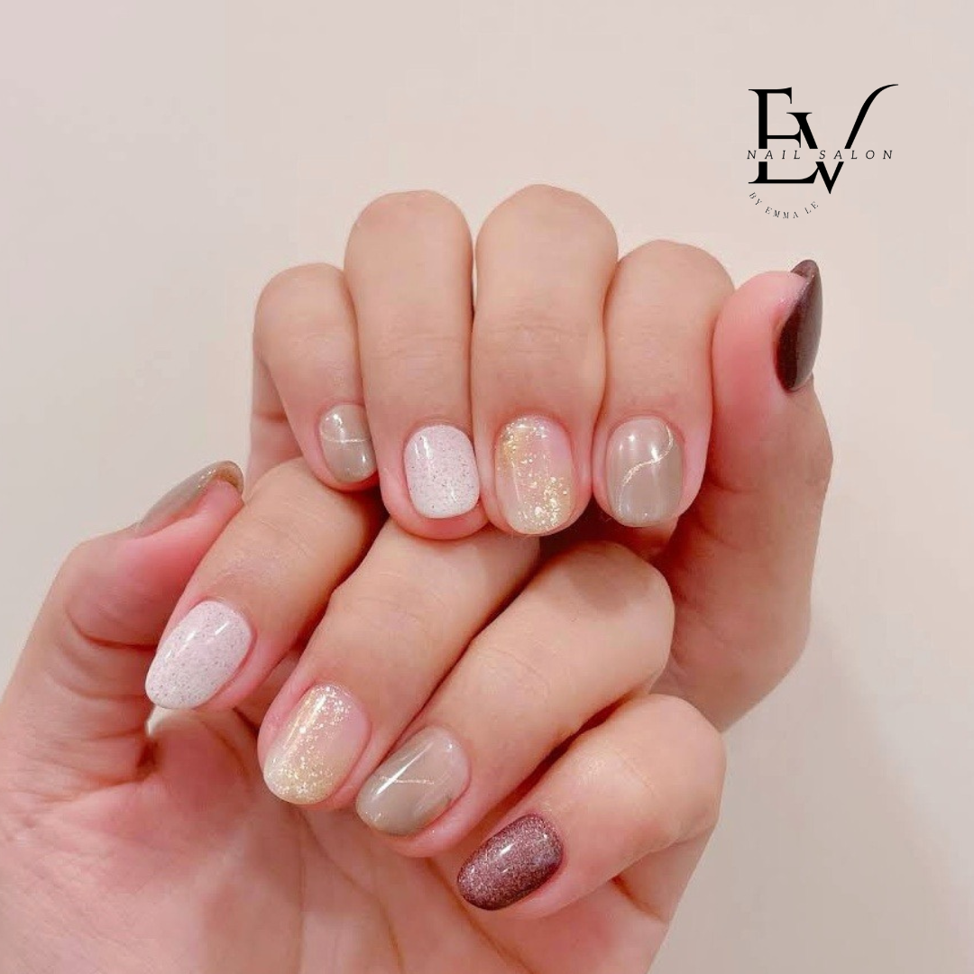 A close-up of a hand showcasing a stylish manicure with various nail polish designs and colors.