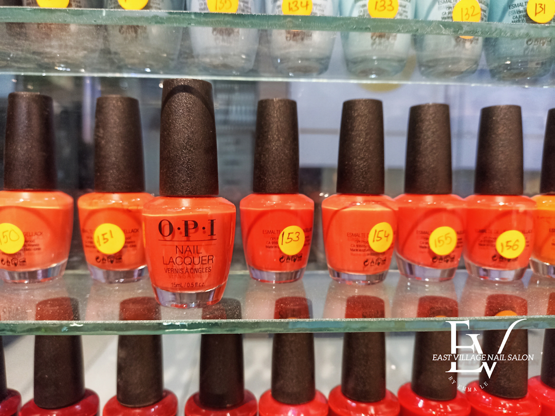 A close-up view of shelves showcasing a vibrant collection of orange and red nail polish bottles, including OPI.