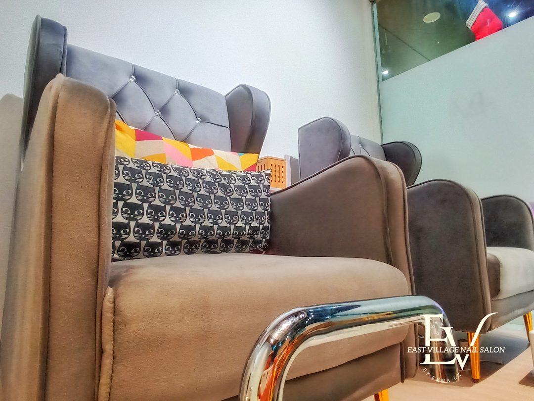 A row of comfortable, plush chairs with decorative pillows inside EV Nail Salon's waiting area.