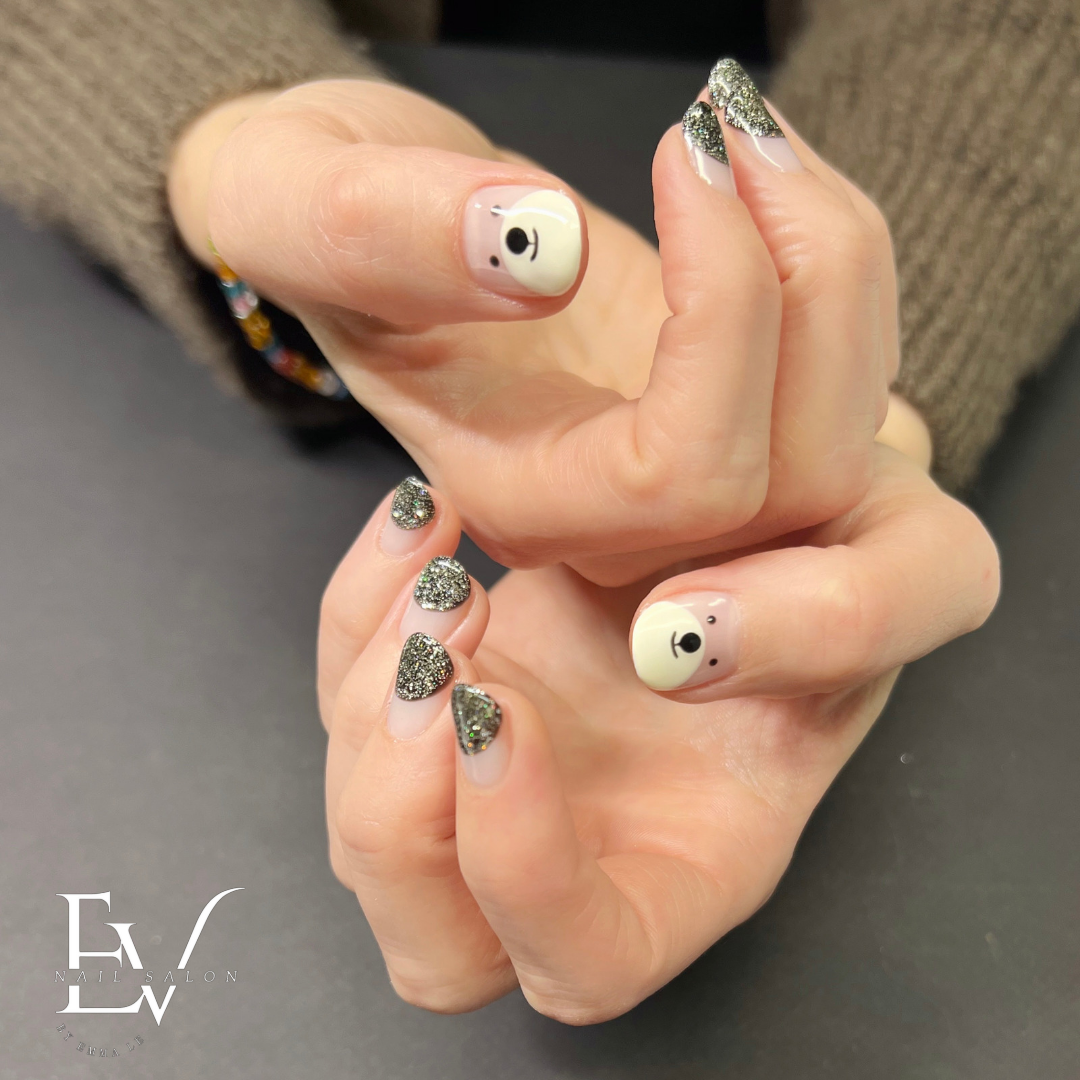 Close-up of hands showcasing a creative manicure with glitter tips and cute bear nail art.