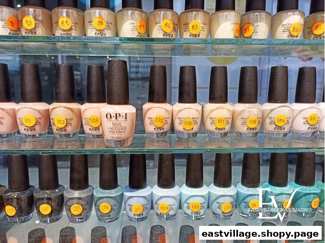 A close-up view of various OPI nail lacquer bottles displayed on glass shelves at a nail salon.
