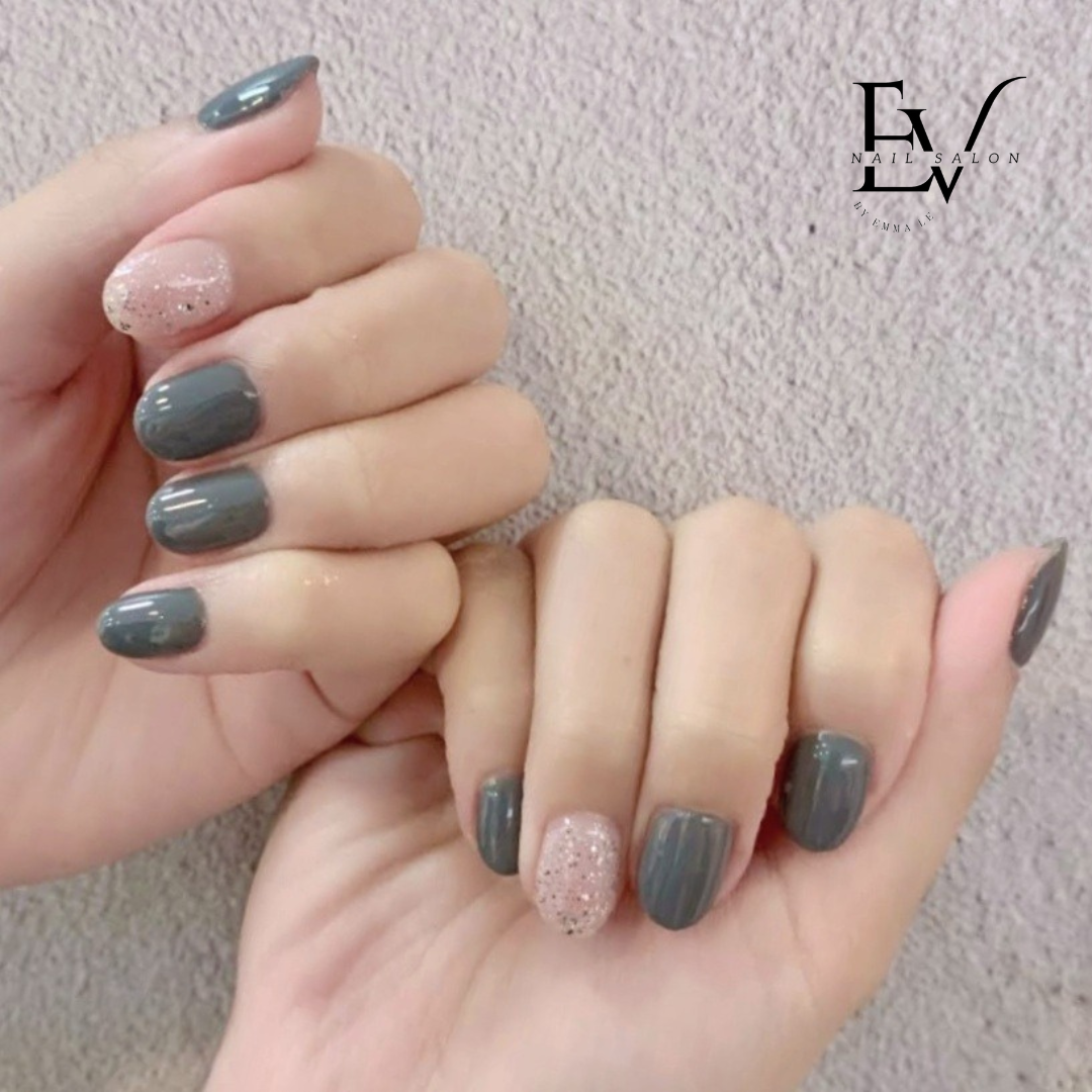 Close-up of hands showcasing a stylish manicure with grey and glitter pink nail polish.