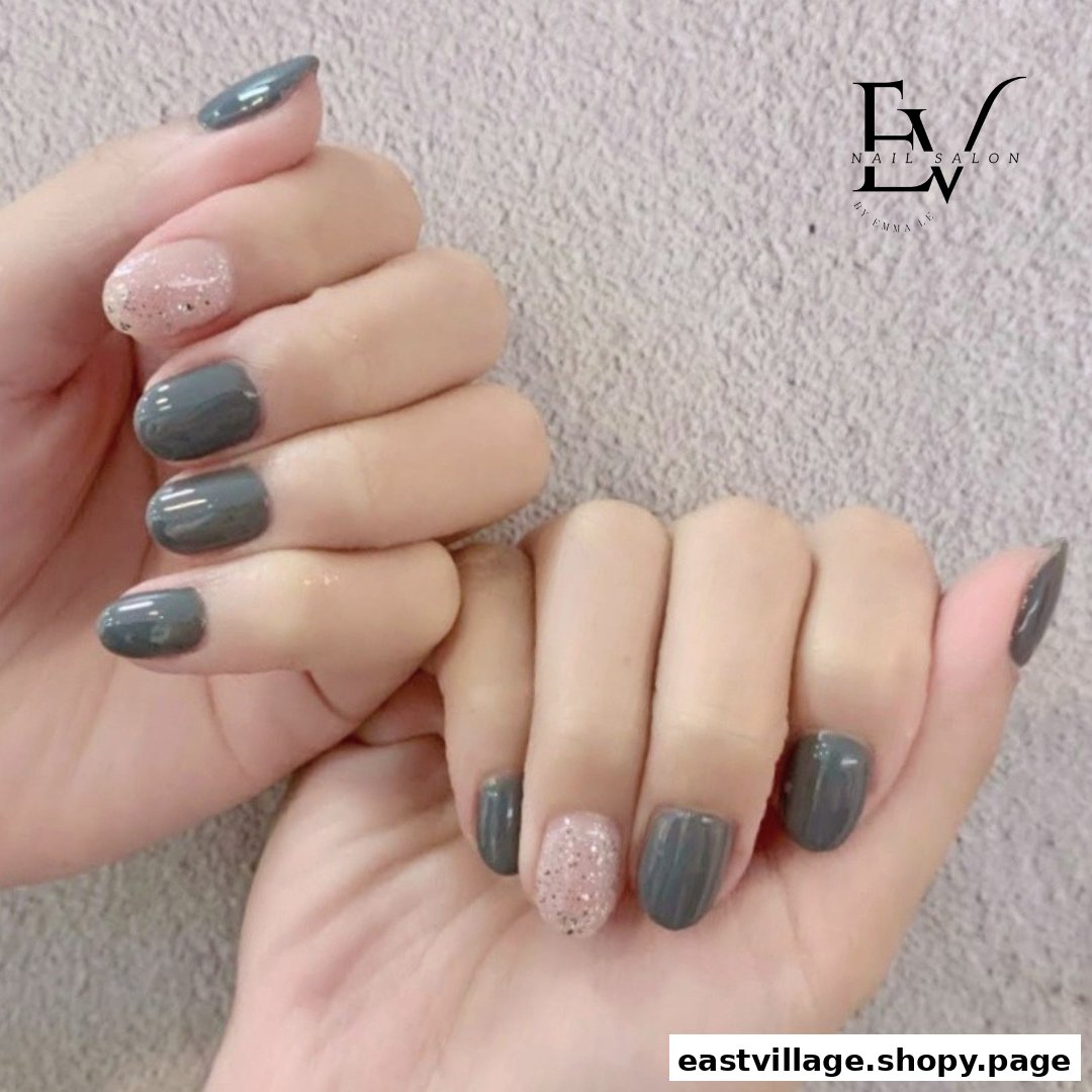 Close-up of hands showcasing a stylish manicure with grey and glitter pink nail polish.