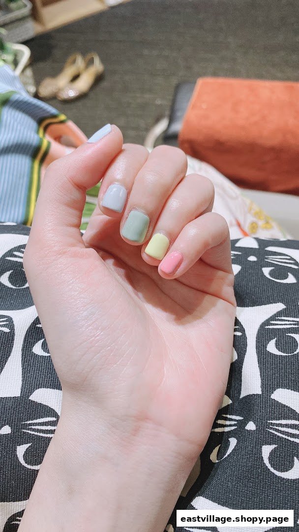 A close-up of a hand showcasing nails painted in various pastel colors, highlighting a fresh manicure.