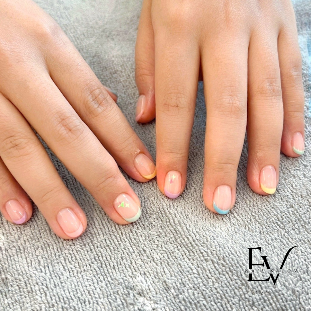 Close-up of hands showcasing a pastel French tip manicure with subtle glitter star accents.