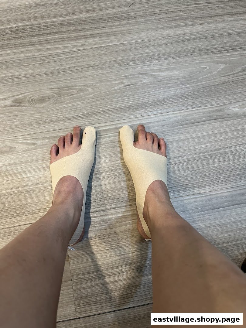 A person's feet wearing specialized toe alignment or bunion correction devices on a wooden floor.