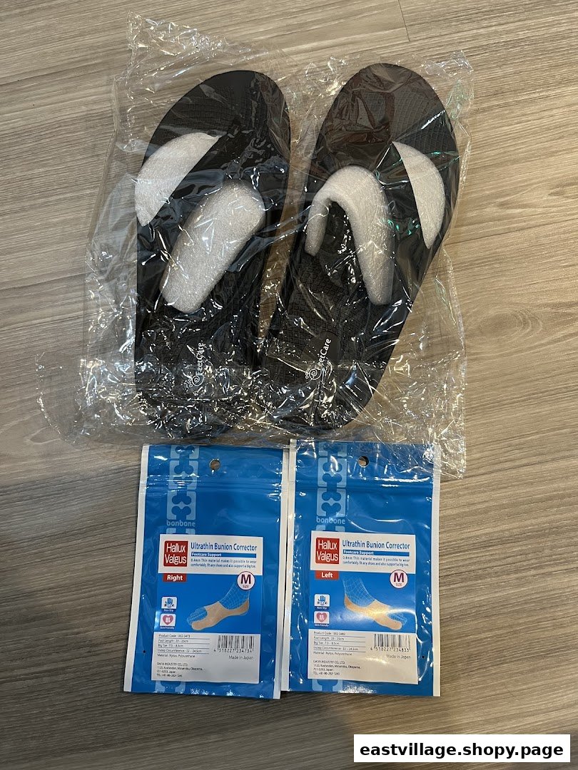 Packaged black slippers and bunion corrector inserts displayed on a wooden floor.