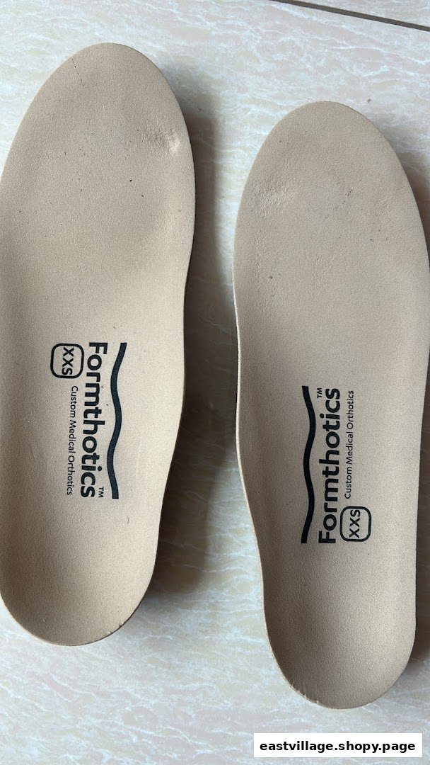 Two beige Formthotics custom medical orthotics insoles, size XXS, on a tiled surface.