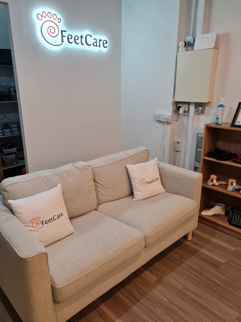 A comfortable waiting area inside FeetCare East Village, featuring a sofa and the illuminated brand logo.