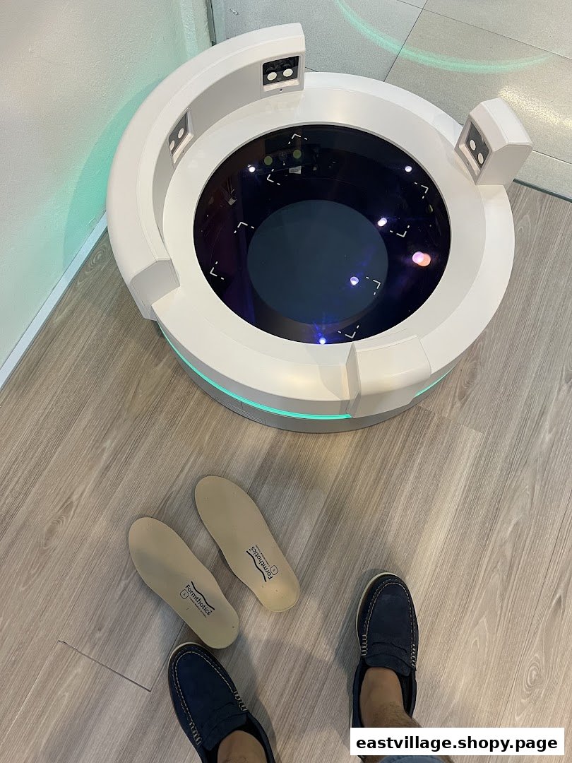 A person's feet and insoles next to a foot scanning machine on a wooden floor.