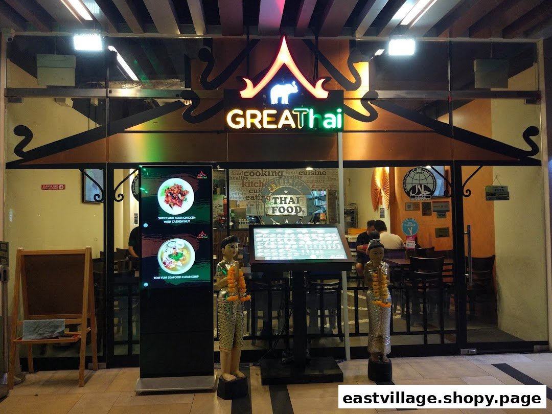 The illuminated storefront of GreaThai, a Thai restaurant, featuring digital displays and traditional decor.
