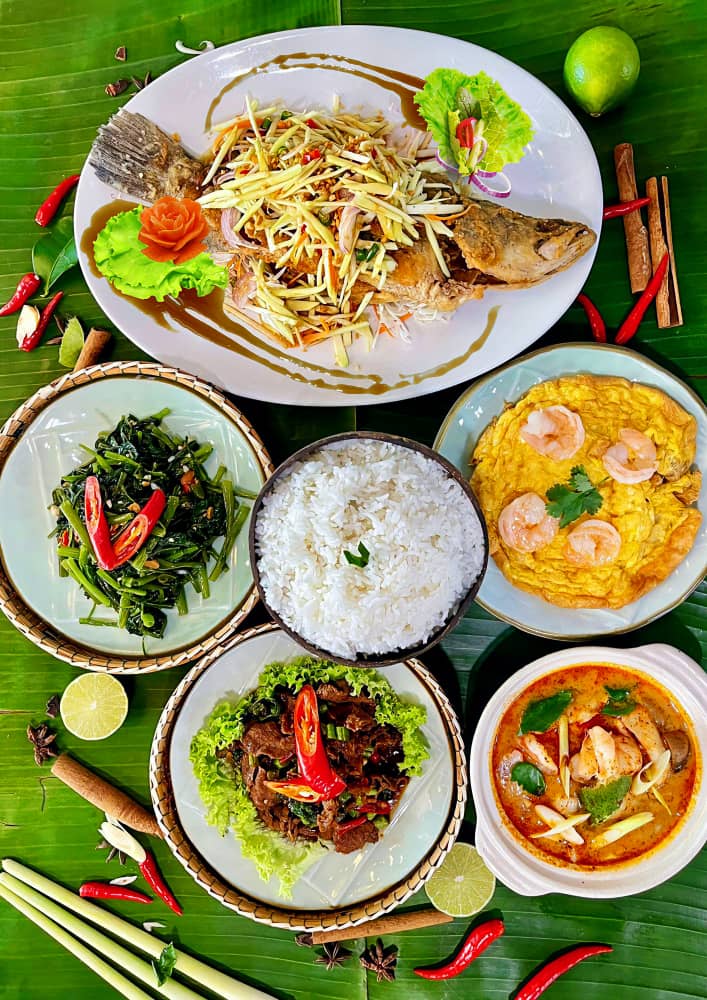 A vibrant spread of authentic Thai dishes, featuring fish, rice, and various flavorful curries.