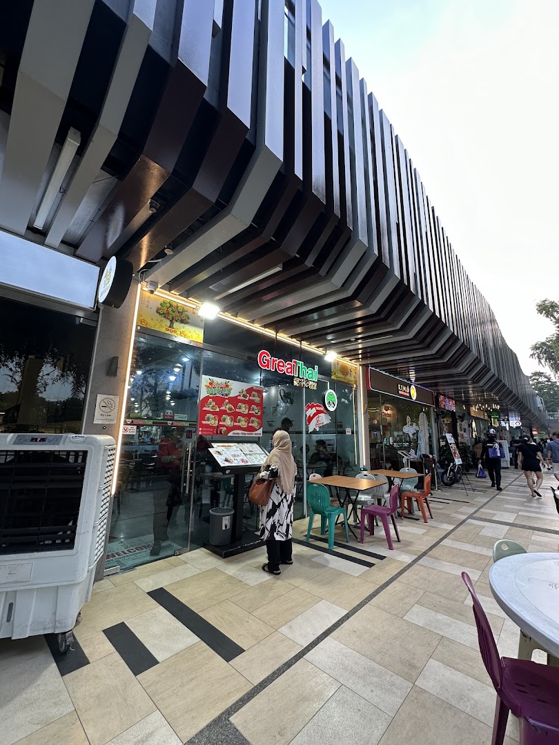 A person views the menu outside GreaThai, a Thai restaurant with outdoor seating.