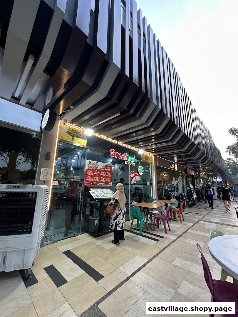 A person views the menu outside GreaThai, a Thai restaurant with outdoor seating.