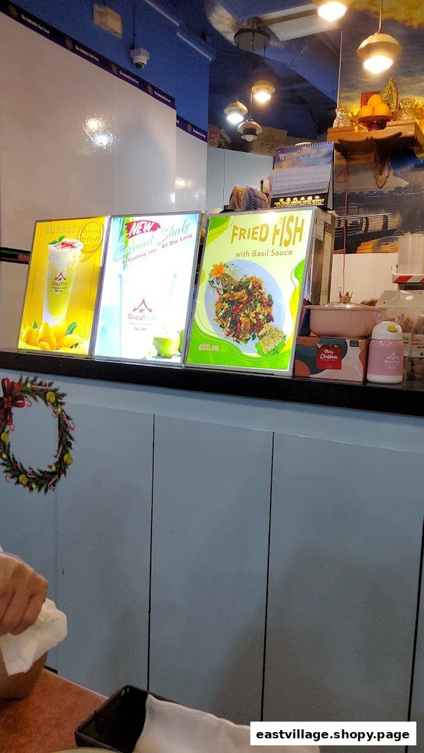 A counter inside GreaThai featuring illuminated display boards showcasing food and drink items.