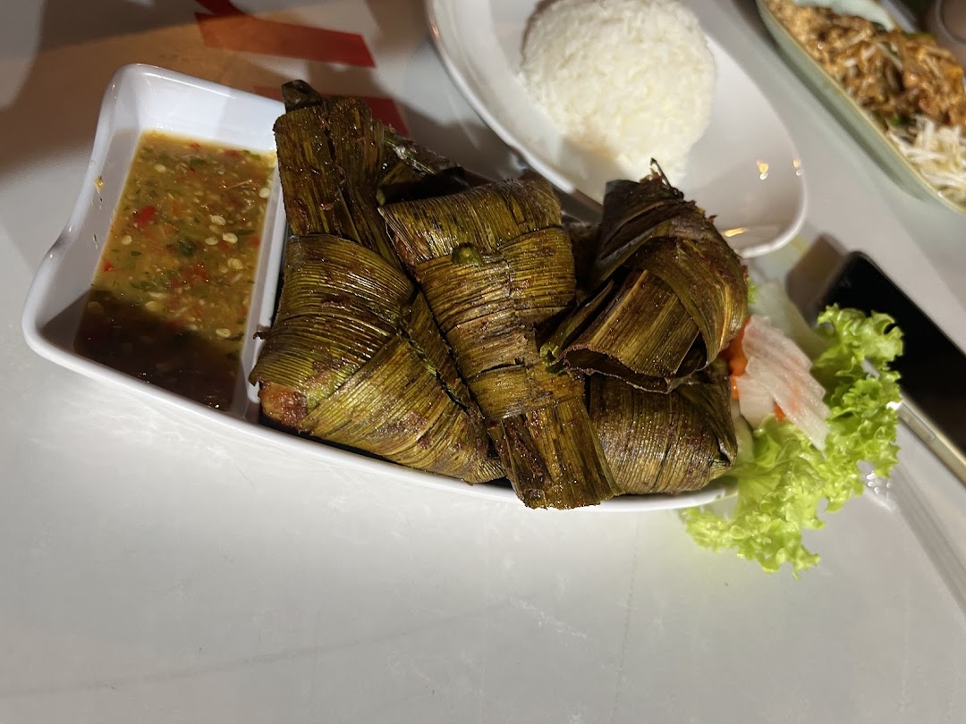 A plate of GreaThai's signature pandan chicken with a spicy dipping sauce and fresh greens.