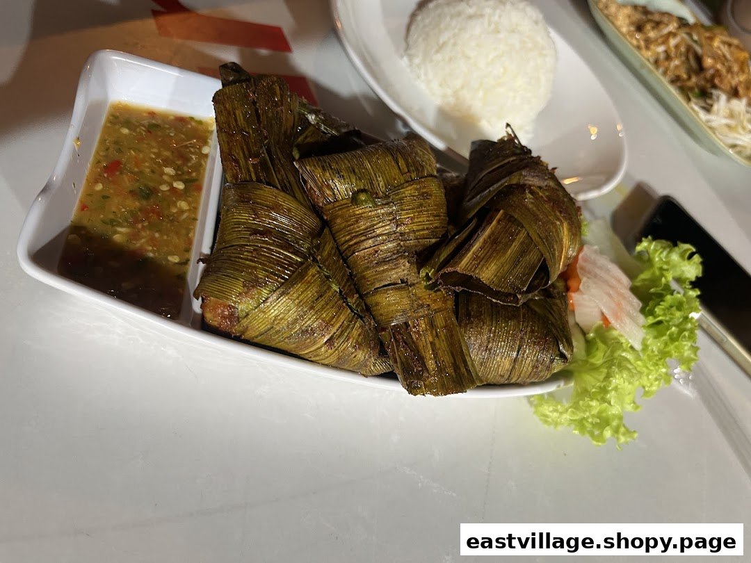 A plate of GreaThai's signature pandan chicken with a spicy dipping sauce and fresh greens.