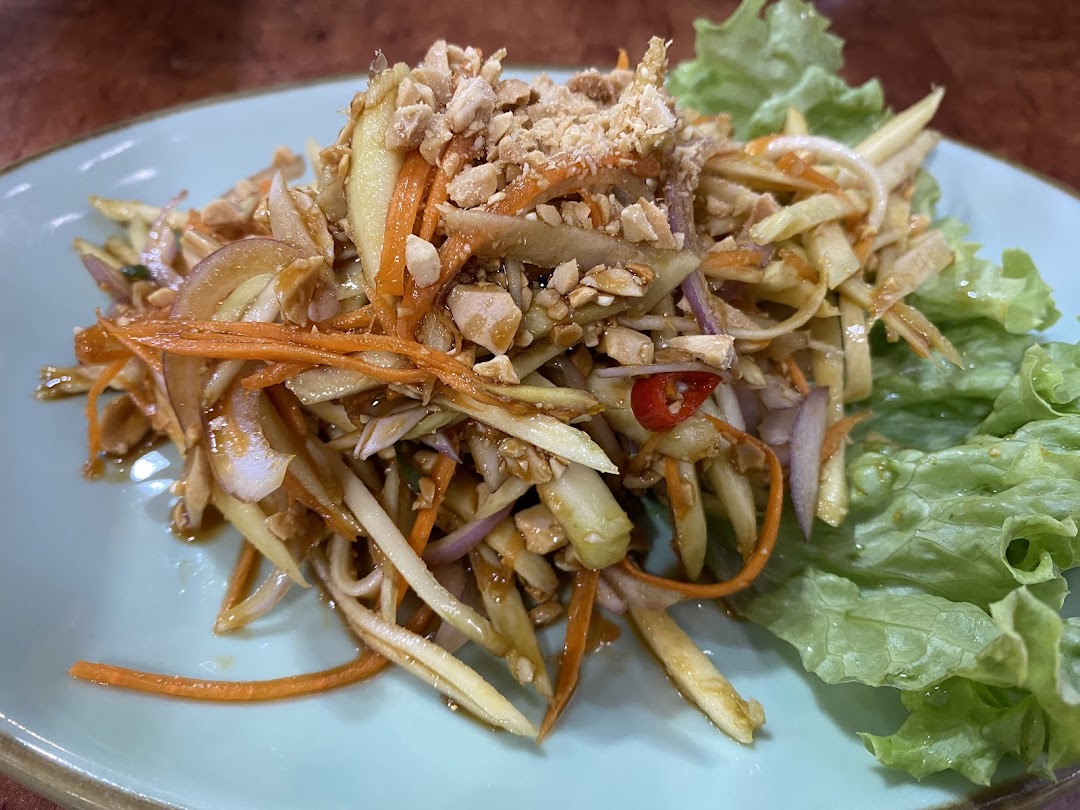 A vibrant Thai mango salad with shredded mango, carrots, red onions, chili, and crushed peanuts.