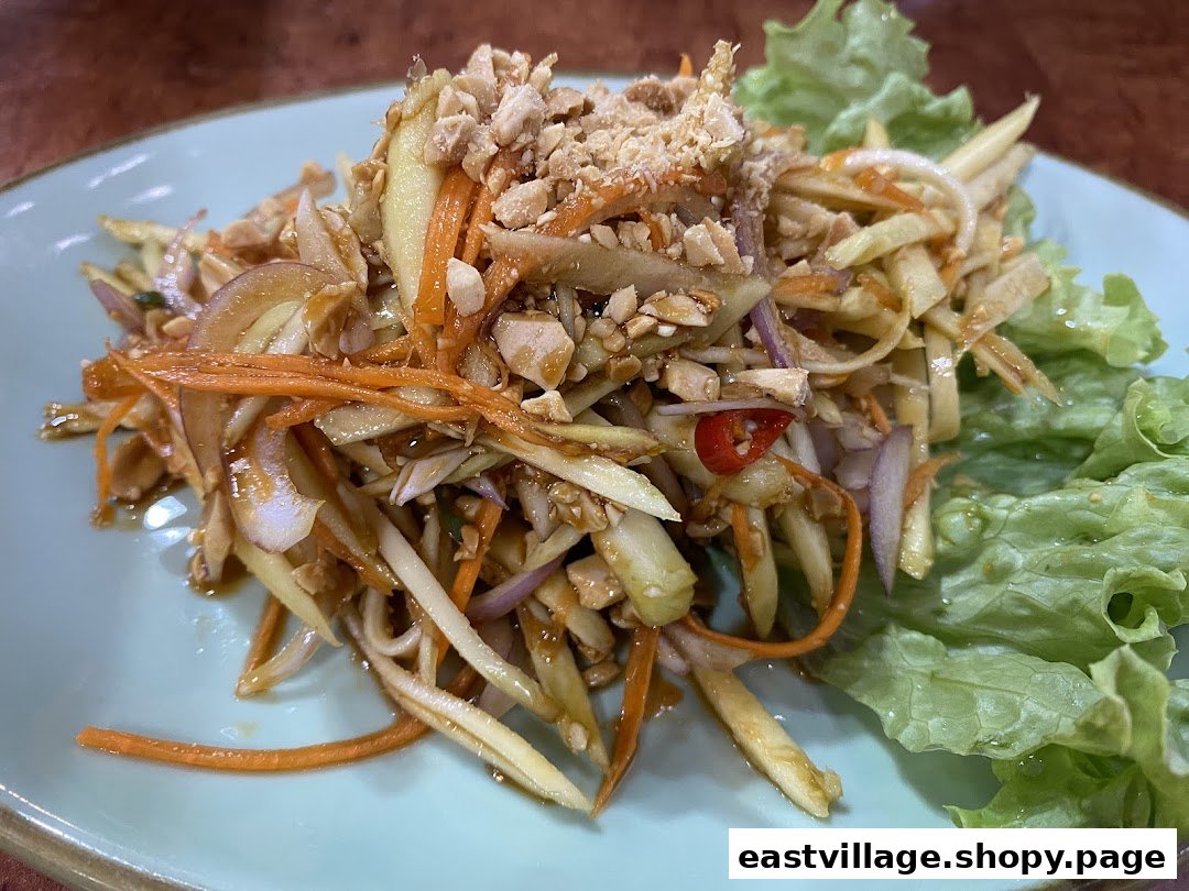 A vibrant Thai mango salad with shredded mango, carrots, red onions, chili, and crushed peanuts.