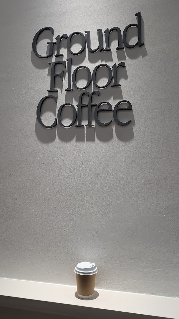 The 'Ground Floor Coffee' sign is displayed on a wall, with a coffee cup resting below it.