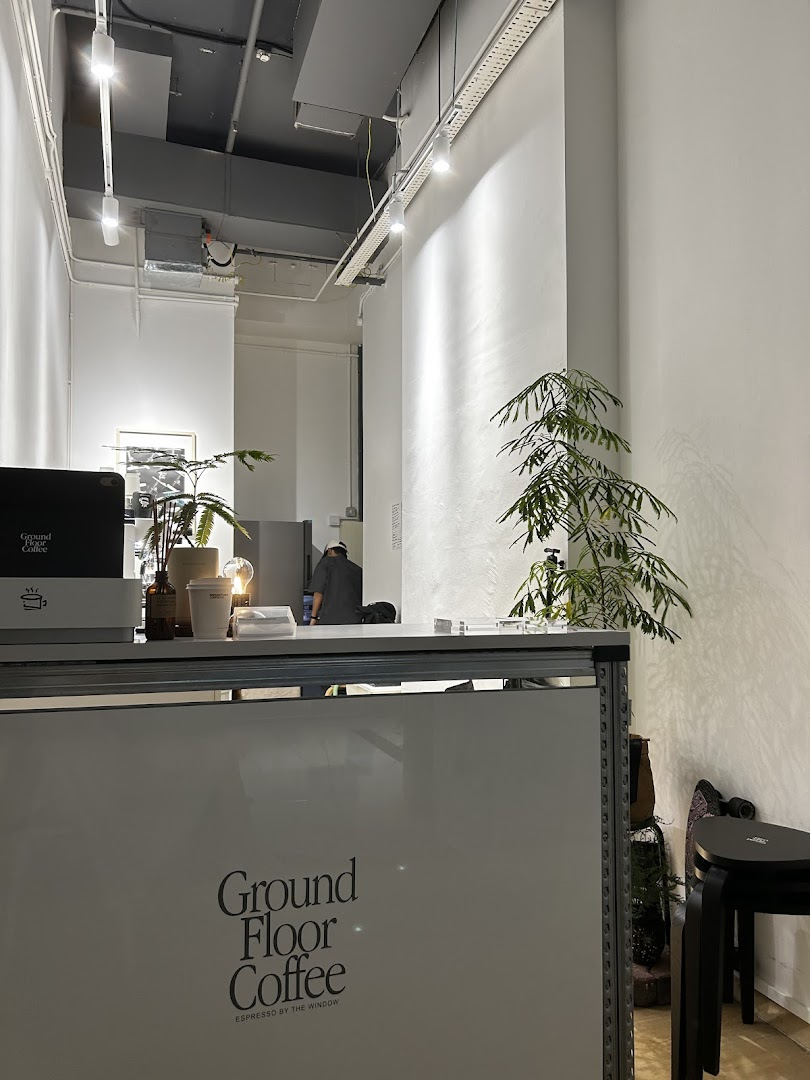 An interior view of Ground Floor Coffee, featuring the minimalist counter and a staff member.