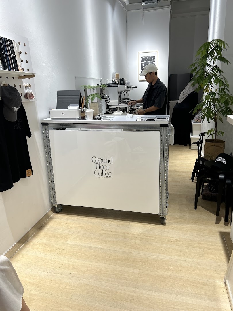 A barista prepares coffee at the minimalist counter of Ground Floor Coffee.