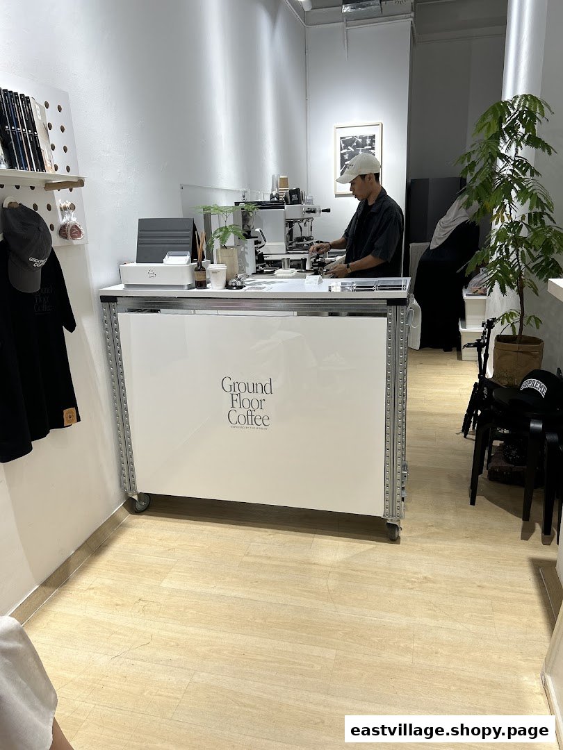 A barista prepares coffee at the minimalist counter of Ground Floor Coffee.
