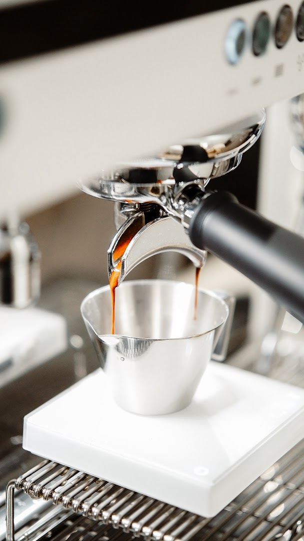 Close-up of an espresso machine brewing fresh coffee into a metal cup at Ground Floor Coffee.