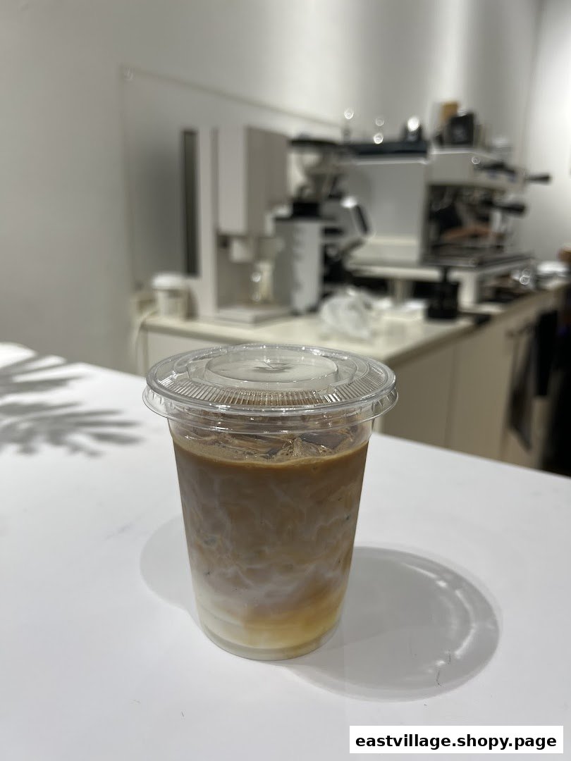 An iced coffee drink with layered milk and coffee on a white counter, with coffee equipment in the background.