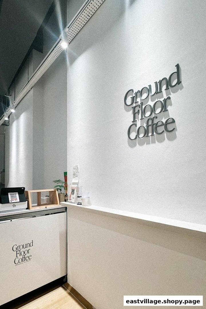 A clean, modern interior view of Ground Floor Coffee, featuring its prominent wall signage and counter area.