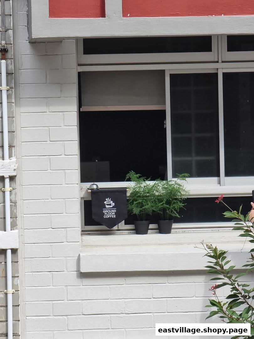 A window display featuring the 'Ground Floor Coffee' banner, potted plants, and a service bell.