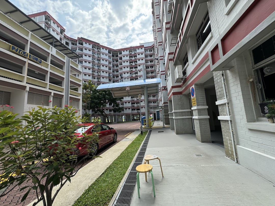 A view of a residential building's ground floor and surrounding pathway, suggesting a local neighborhood setting.