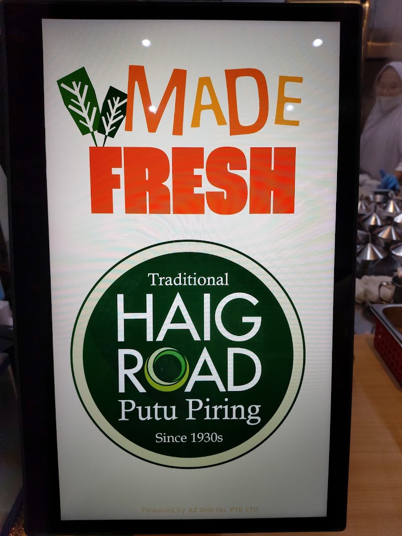 A digital display board for Haig Road Putu Piring, highlighting 'Made Fresh' and its traditional heritage.