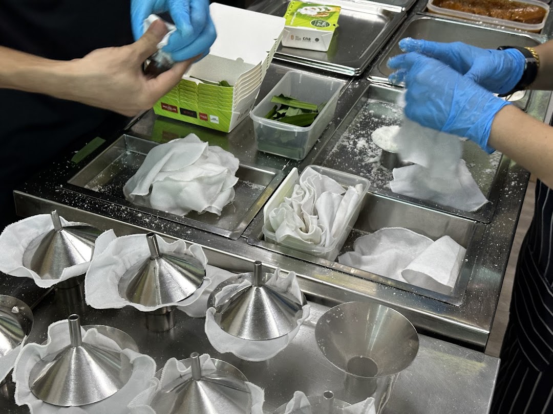Hands preparing putu piring with traditional tools and ingredients in a clean kitchen.
