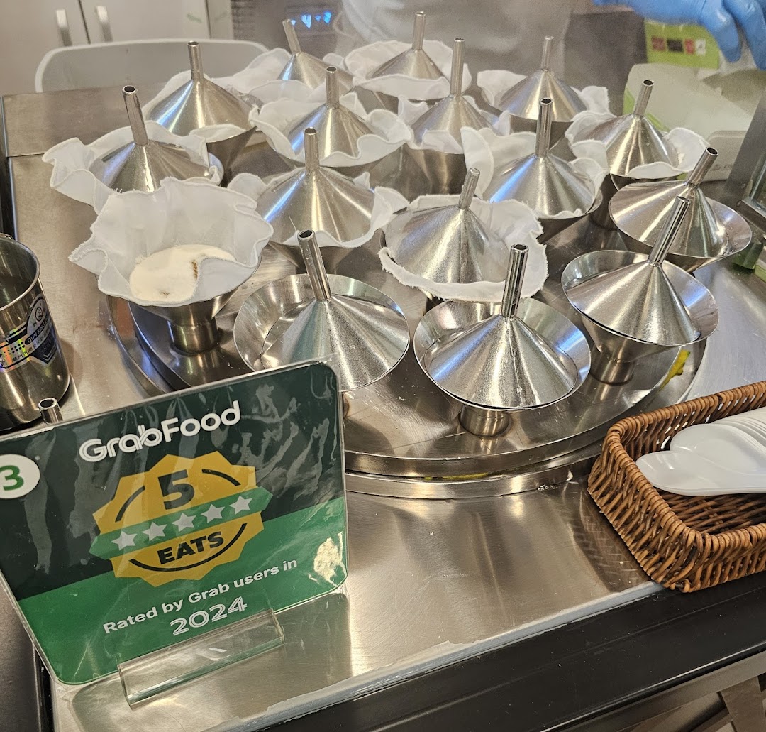Close-up of putu piring molds with batter, ready for steaming, alongside a GrabFood 5-star rating sign.