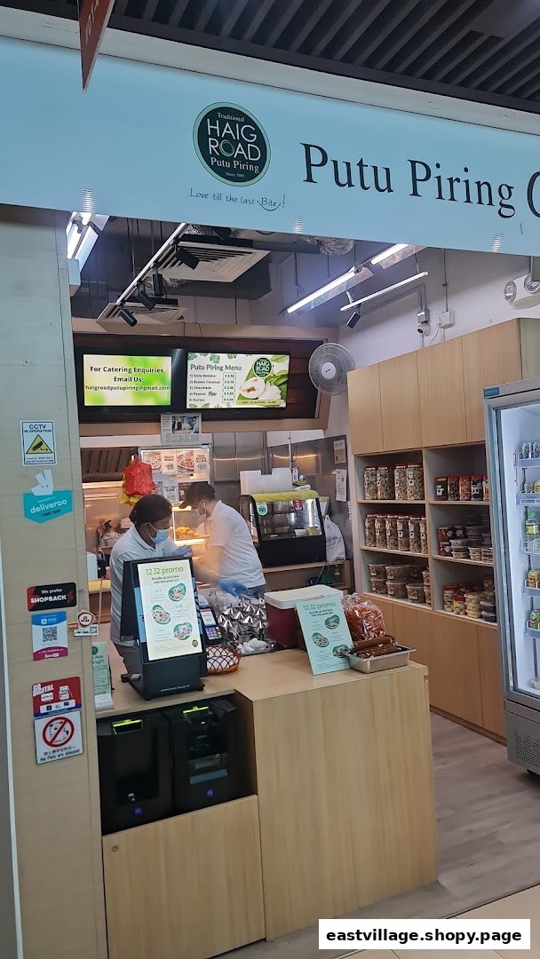 Interior view of Haig Road Putu Piring, showing staff, traditional snacks, and a menu display.