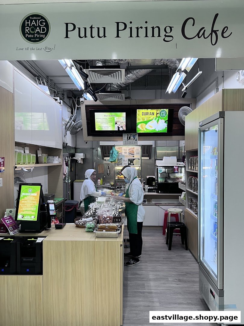 Two staff members serve customers at the counter of Haig Road Putu Piring Cafe.