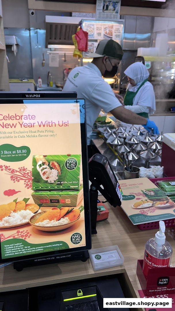 A promotional display for Haig Road Putu Piring's New Year offer, with staff preparing food.