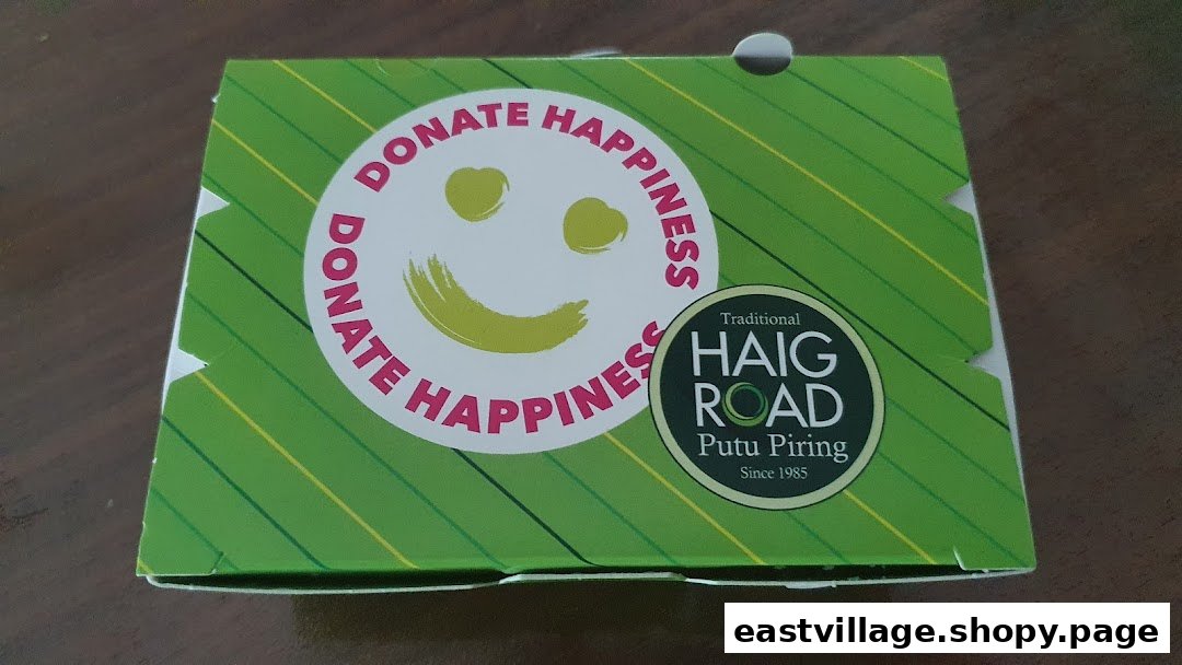 A green product box from Haig Road Putu Piring featuring a 'Donate Happiness' smiley logo.